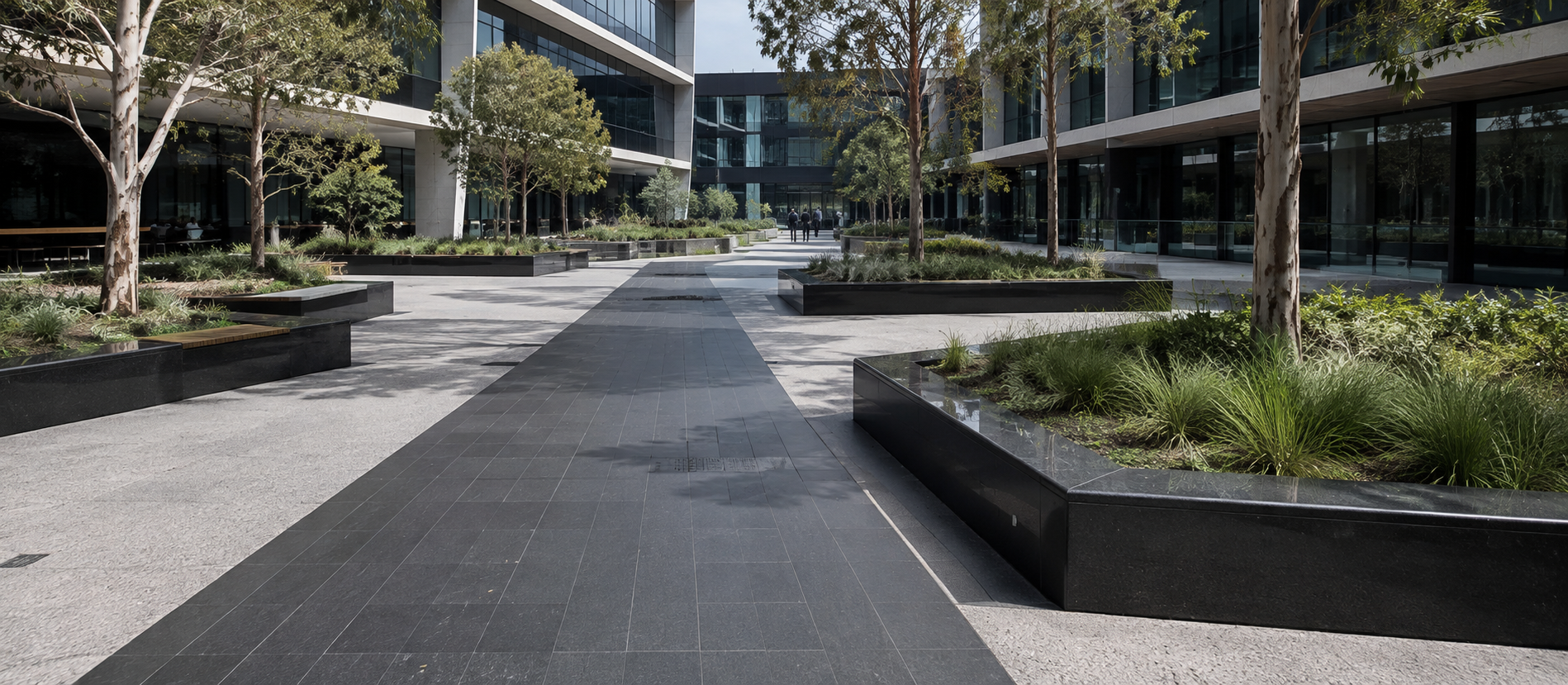 Dark stone paving and planter edges outside a modern building